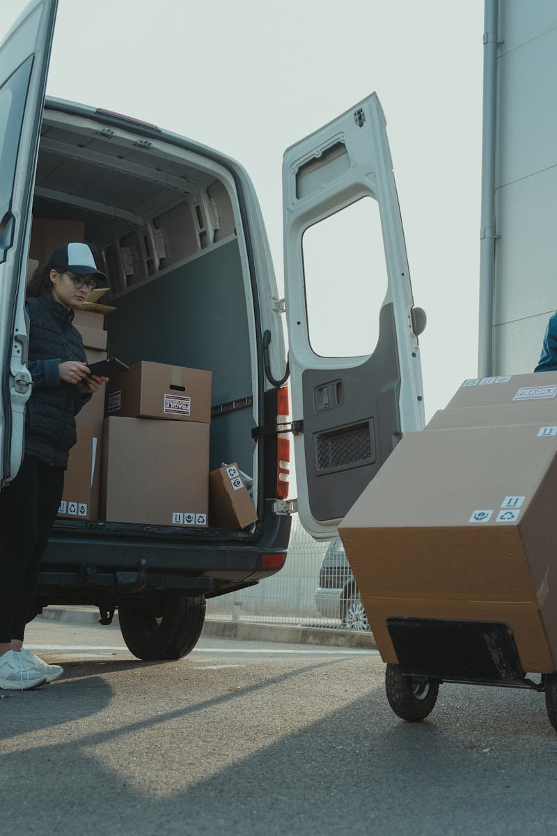 Two couriers load boxes into a van for shipment, showcasing logistics and teamwork.